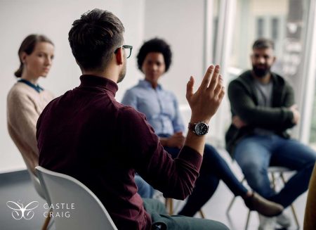 Rear view of man with raised hand on group therapy in medical center.|Pros (2)|Specialisations at CATCH (1)|Pros (2000 × 1500px)|1|2|Individual CBT & DBT therapy (1)|Untitled design (1)|Untitled design (2)|Pros (2000 × 1500px) (1)|Horizontal services and goals|grup therapy session holding hands