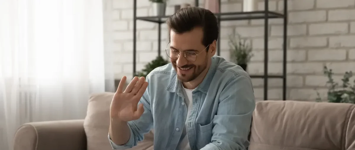 Man waving at laptop during online therapy for alcoholism