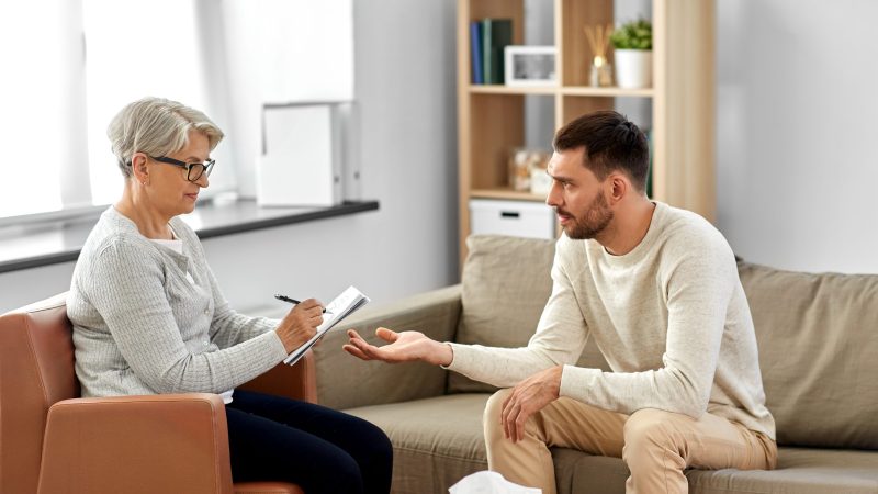 senior woman psychologist and sad man patient