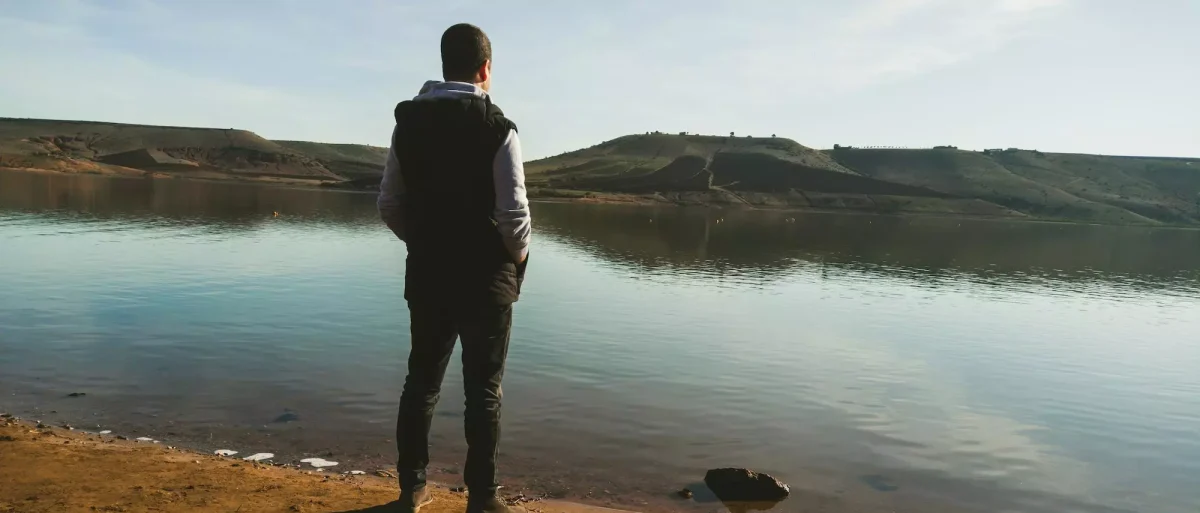 Man standing looking onto lake during the day