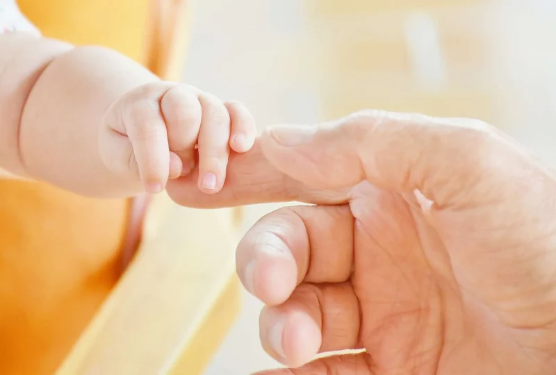 a baby hand holding an adult hand