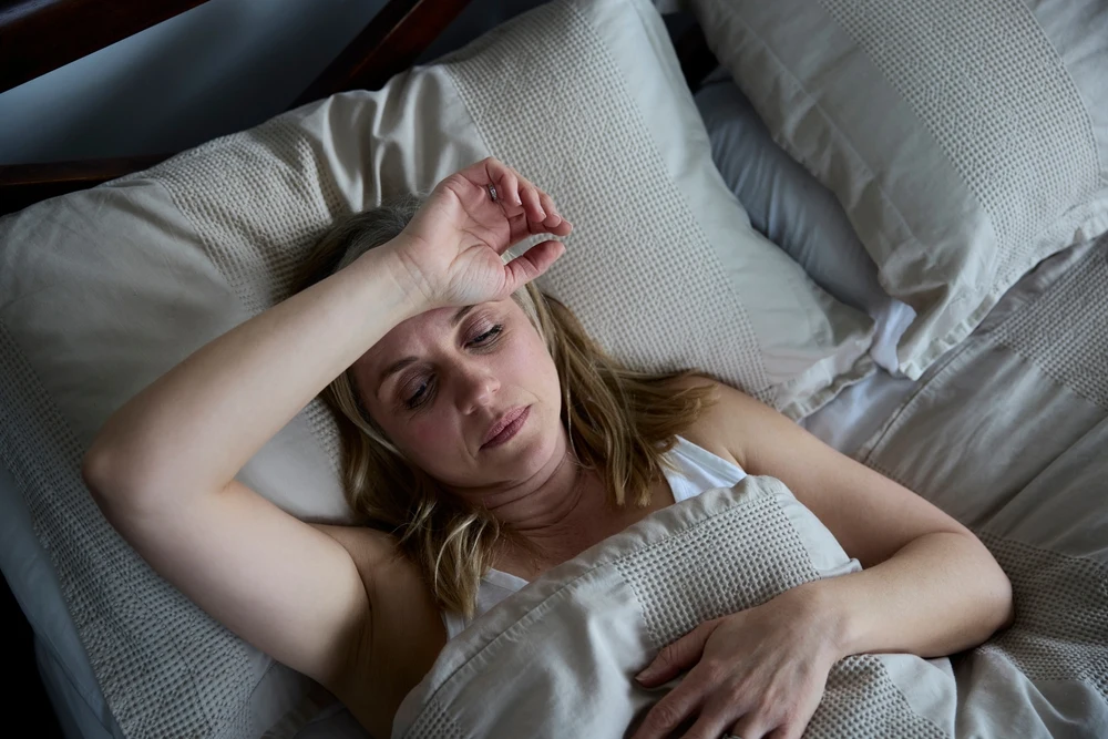 A woman struggling in bed with alcohol sweats.