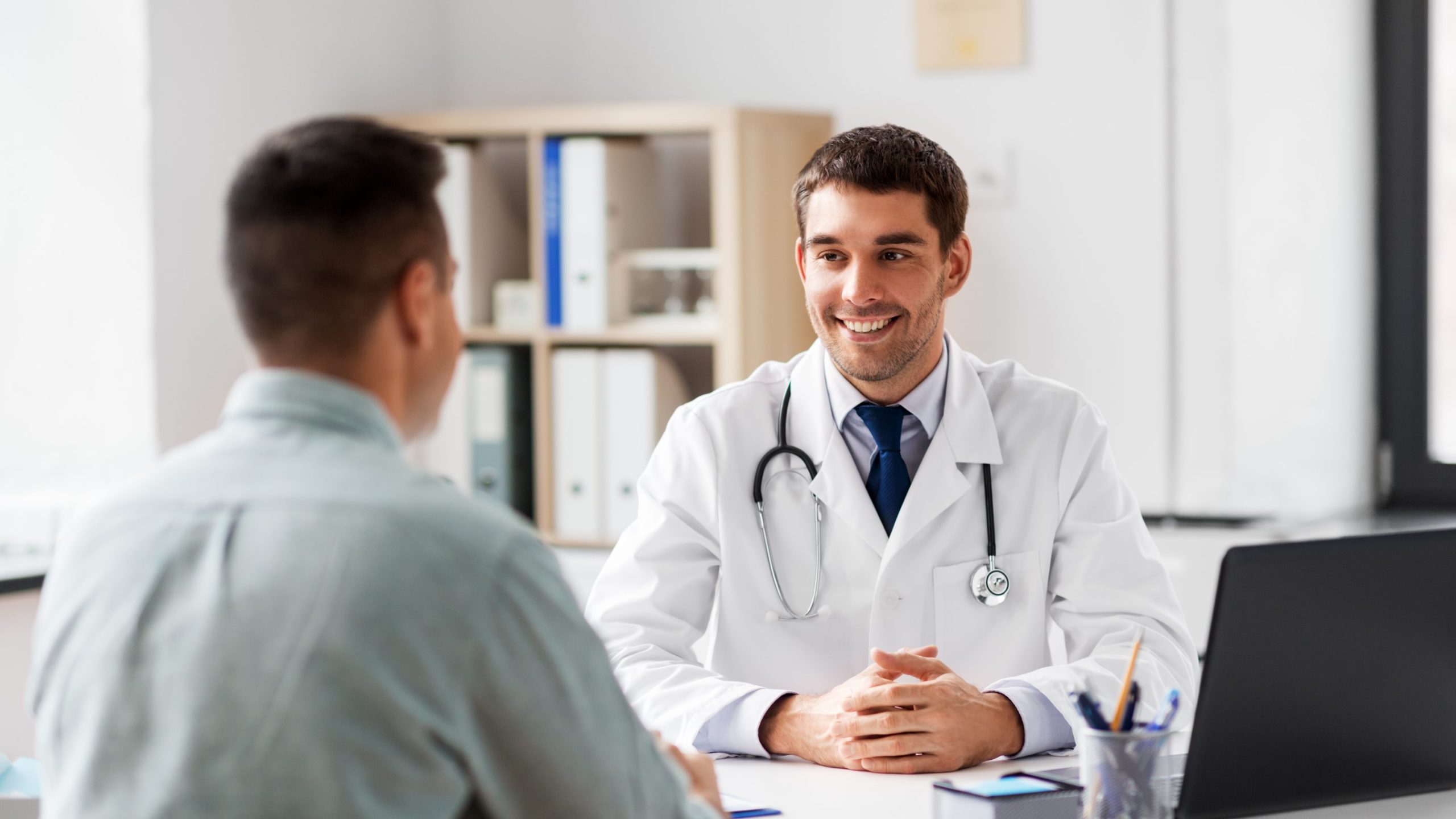 Doctor with laptop and male patient at hospital